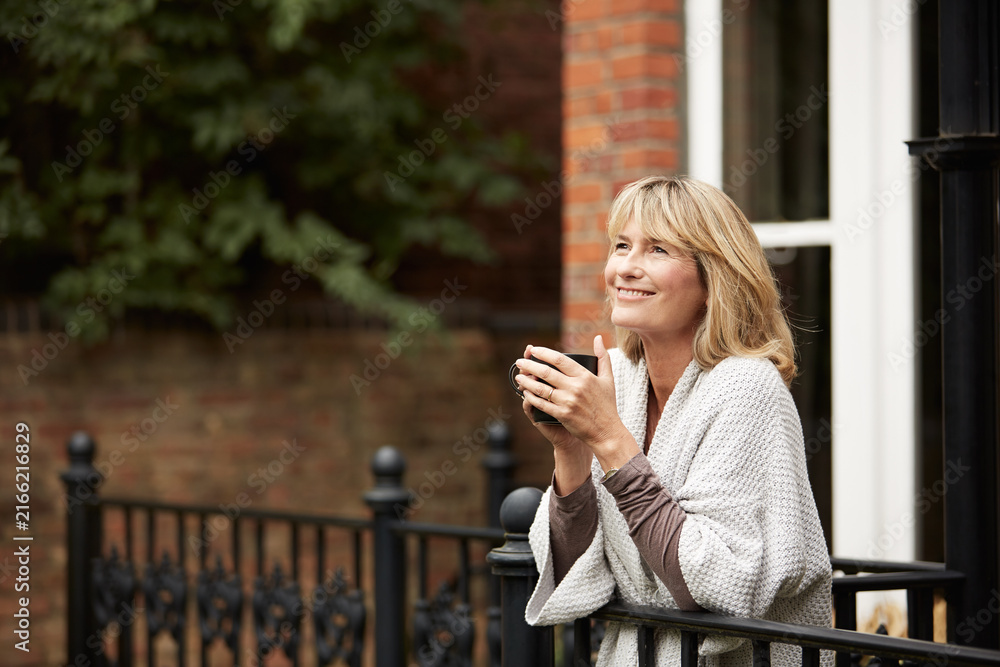 Fototapeta premium Coffee, home and thinking with happy woman on balcony for morning break, contemplation or vision. Drink, reflection and smile with mature person outdoor on terrace for memories, nostalgia or planning