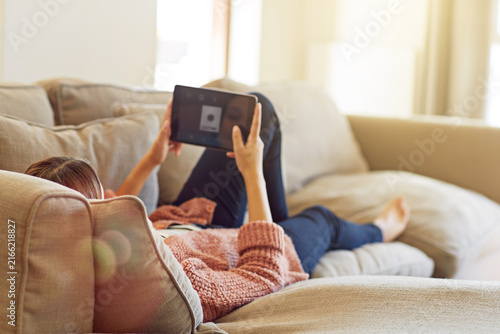 Woman  tablet screen and relax on sofa for social media  streaming movie and scroll in living room. Female person  website and subscription on couch for online  search or reading ebook in apartment