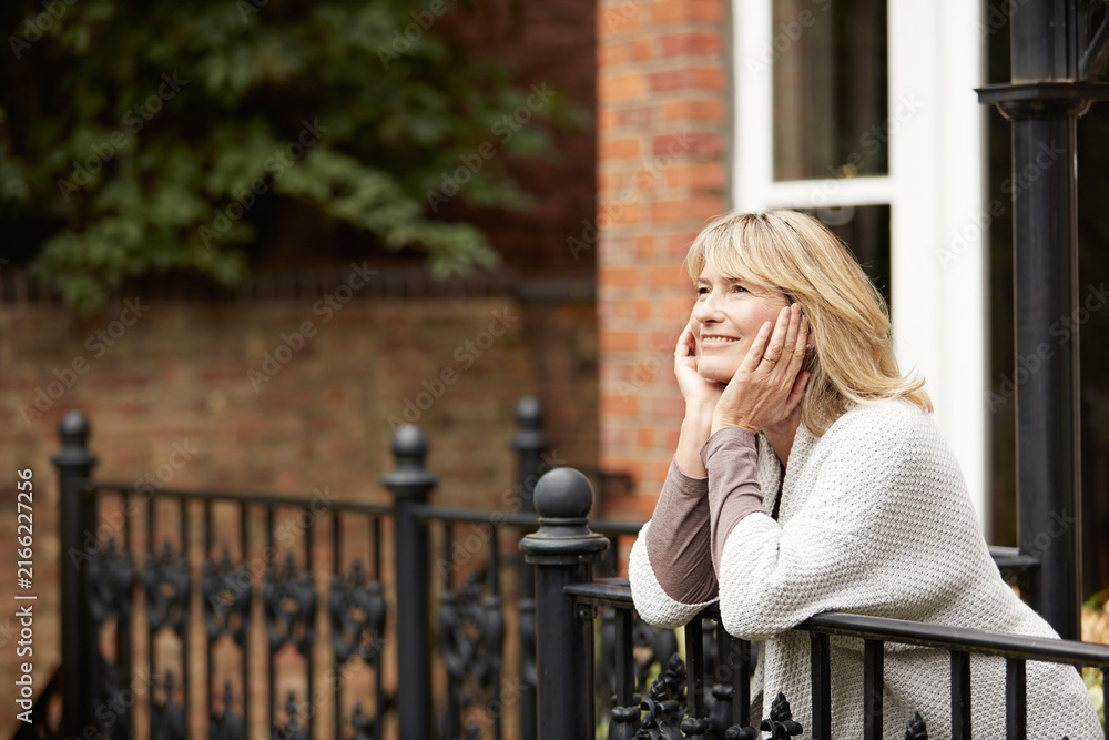 Fototapeta premium Happy, thinking and woman on balcony of holiday home for morning break, relax or vision. Smile, ideas and reflection of mature person on terrace of apartment for memories, nostalgia or planning