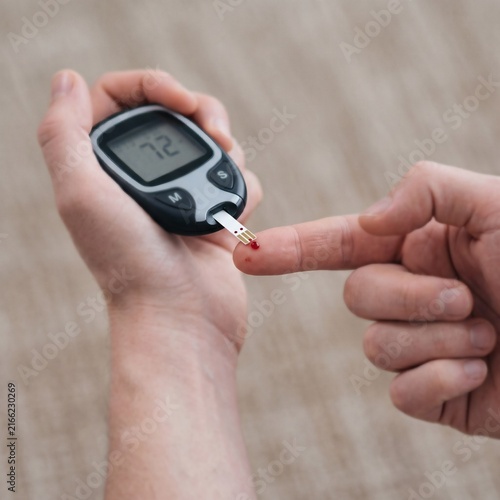 Person checking blood glucose level with a digital glucometer monitor