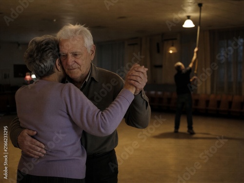 Senior man and woman dancing together in a cozy ballroom. Elderly couple enjoying companionship, romance, social activity, and an active lifestyle in retirement.
