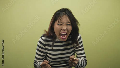 Foto Woman with mouth open shouting, hands clutching head and fists raised in studio; raw frustration release