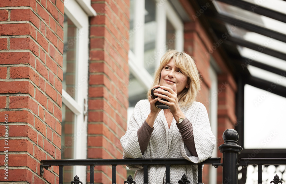 Fototapeta premium Coffee, reflection and woman on balcony of home for morning break, contemplation or vision. Drink, ideas and thinking with mature person on terrace of apartment for memories, nostalgia or planning