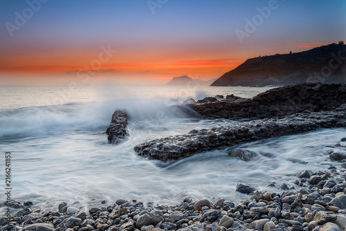 Foto Sunbeams breaking through dark storm clouds over the sea with distant ships and