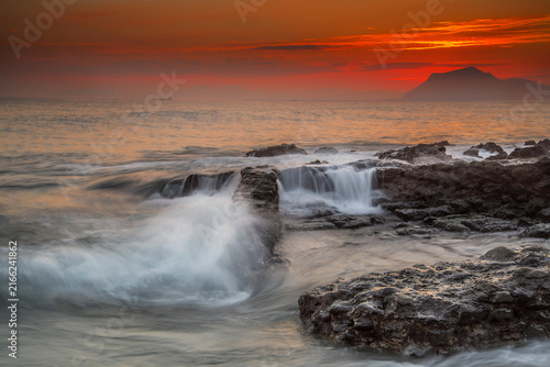 Bild auf Leinwand Sunbeams breaking through dark storm clouds over the sea with distant ships and