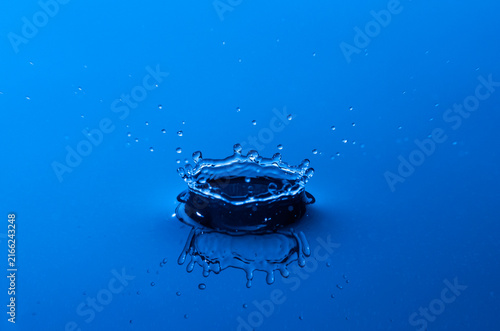 Cuadro en lienzo Close up f crown shaped water drop splash and reflection in blue light