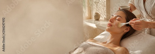 Woman receiving facial massage with brush at a beauty spa. Skincare treatment and self care concept with generous copy space for beauty banner design and wellness advertising.