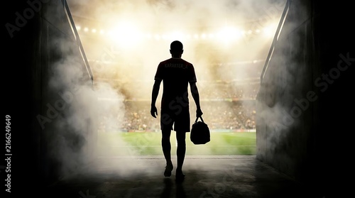 Silhouette of athlete walking into smoky stadium arena.
