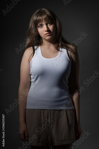Portrait of a young woman in white tank top looking at camera with serious expression