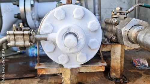 Extreme freezing on industrial pipeline flange covered in thick white ice and cold vapor from a cryogenic liquid system