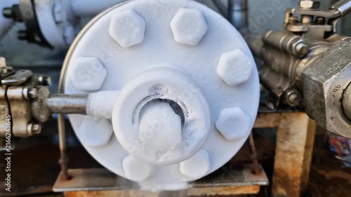 Heavy duty industrial pipeline flange heavily frozen with thick white frost and cold vapor in cryogenic liquid system