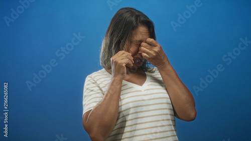 Canvastavla Woman removes glasses and pinches bridge of nose holding spectacles in studio after rubbing eyes for apparent eye strain and headache; fatigue relief