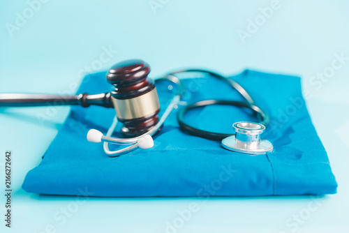 Bild auf Leinwand Judge gavel and stethoscope arranged on blue medical scrubs, representing health