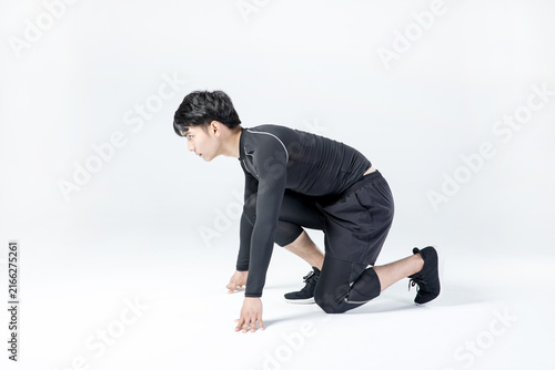 Athletic man in sprint start pose on white background