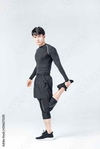 Athletic man stretching leg in sportswear during studio fitness warm up