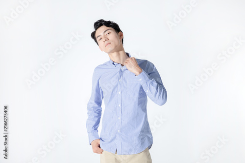Young man adjusting collar in striped shirt on white background