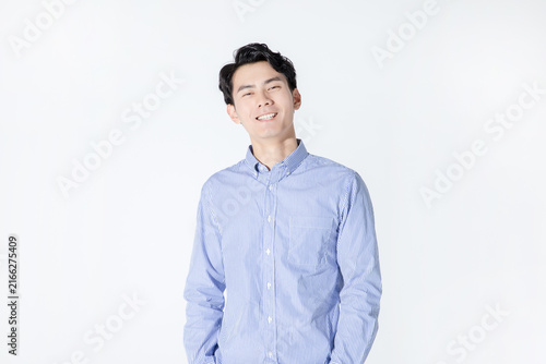 Smiling young man in striped shirt standing against white background