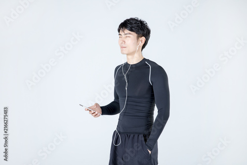 Young athletic man listening to music on smartphone in sportswear