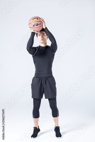 Young man holding basketball in shooting position in studio