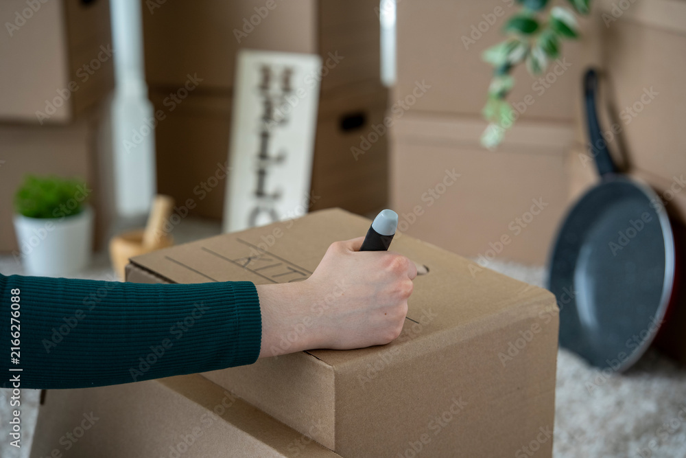 Fototapeta premium Woman Labeling Moving Box as Kitchen During Home Relocation