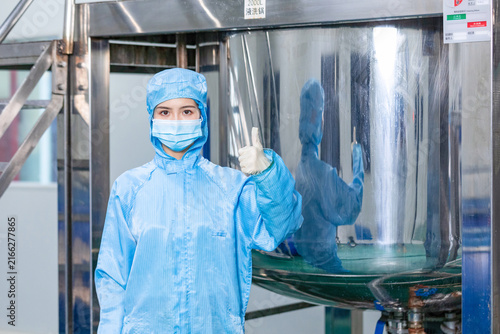 Female cleanroom technician giving thumbs up in industrial factory