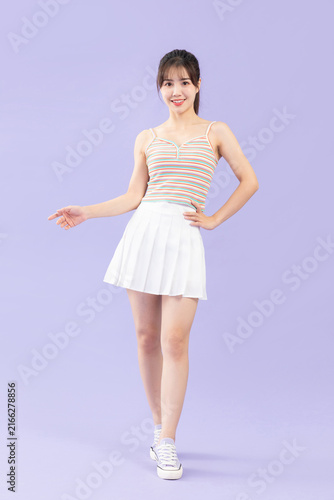 Fotografie Smiling young woman in striped camisole and white skirt posing on pastel purple