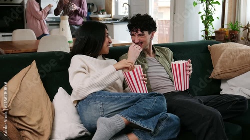 Happy boyfriend and girlfriend relaxing on the couch, eating popcorn and watching television