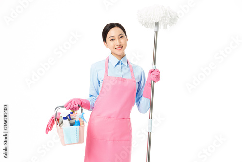 Obraz na plátně Smiling housekeeper with cleaning supplies and feather duster on white
