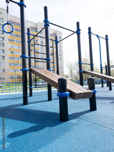 Obraz na plátně Unoccupied outdoor playground with blue posts and wooden ramp beside apartment b