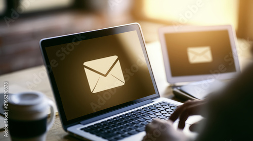 Business professional using digital email marketing interface on laptop and t...