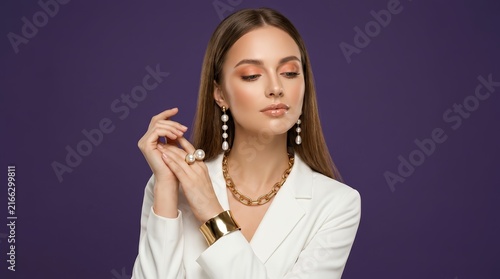 Beautiful young woman showcasing luxury jewelry on a solid purple background.