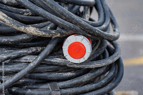 Fotografie Industrial three-phase power cable roll with red heavy-duty plug connector for t