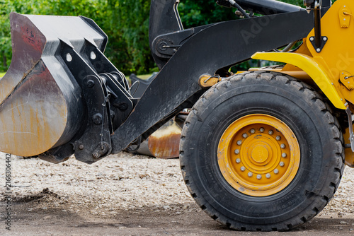 Heavy loader wheel assembly, massive planetary hub bolts, and hydraulic lift arm linkage bucket mechanism on a civil construction site