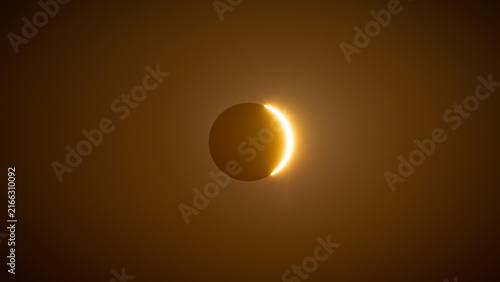 Bild auf Leinwand Thin solar crescent emerging through golden haze during solar eclipse, Spain