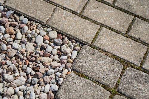 Interlocking concrete paving stones meeting a bed of decorative garden pebbles and gravel landscape edging in a modern courtyard