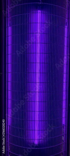 Foto A close‑up of a glowing ultraviolet fluorescent tube encased in a protective metal grid