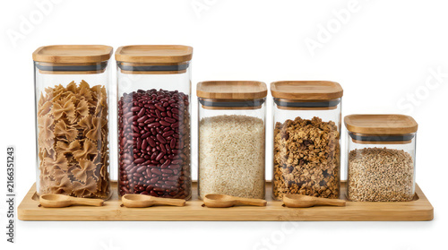 Five glass kitchen canisters with bamboo lids filled with dry goods.
