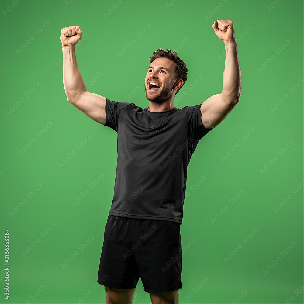 Naklejka premium Excited Athletic Man Celebrating Success With Arms Raised Against Green Screen Background