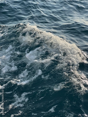 Fotografie Foamy Boat Wake and Ocean Waves Close Up in Blue Sea