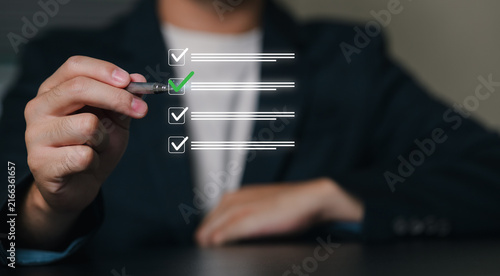 A business professional in formal attire interacts with a transparent digital checklist interface, representing productivity, organization, and task management.