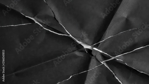 Abstract ripped crumpled black paper texture with white cracks for background design.