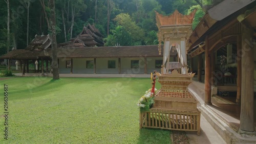 Sacred courtyard with traditional temple buildings at Wat Phra Lat, Buddhist monastery surrounded by tropical forest and peaceful garden lawn, Chiang Mai, Thailand 4k