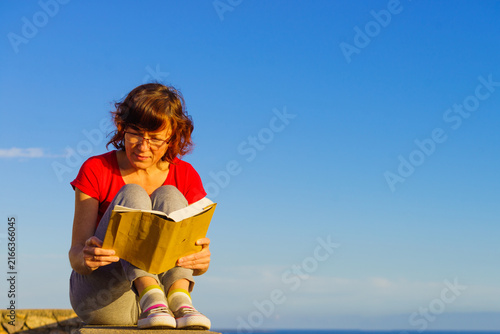Woman outdoors read book, relaxing