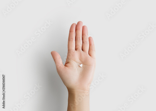 Hand Holding Small White Heart Shaped Pill