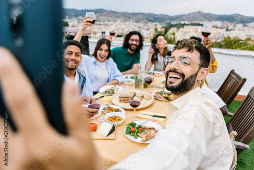Принти на полотні Diverse friends enjoying a celebratory party on an outdoor terrace, raising wine