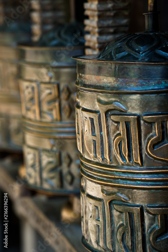 Canvas Print Close-up of ornate Buddhist prayer wheels with embossed Tibetan script, aged metal surfaces, and shallow depth of field, creating an atmospheric cultural and spiritual image in Vienna