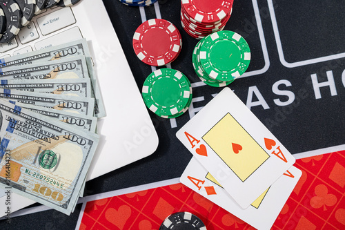 White Laptop with US Dollar Bills Pocket Aces Cards and Casino Chips for Online Gambling Concept