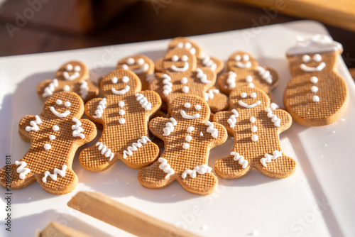 A group of gingerbread man cookies decorated with white icing smiles and buttons rests on a white plate, a festive holiday baking treat.