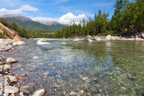 Summer landscape with shore of Irkut River and Eastern Sayan Mountain range in the distance on sunny August day. Natural background. Summer travels. Siberia, Buryatia, Tunka Valley, nature park
