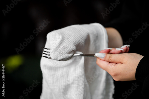 фотографія A close-up of hands polishing a metal fork with a white lint-free cloth against